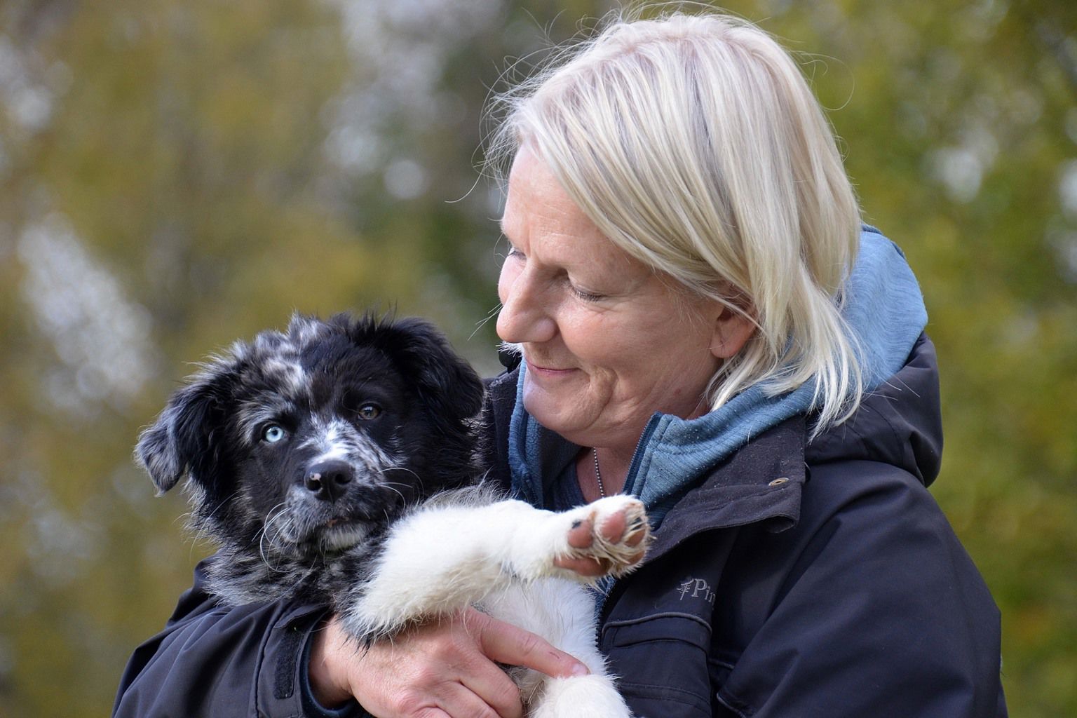 Glad kvinna håller en hundvalp i famnen.